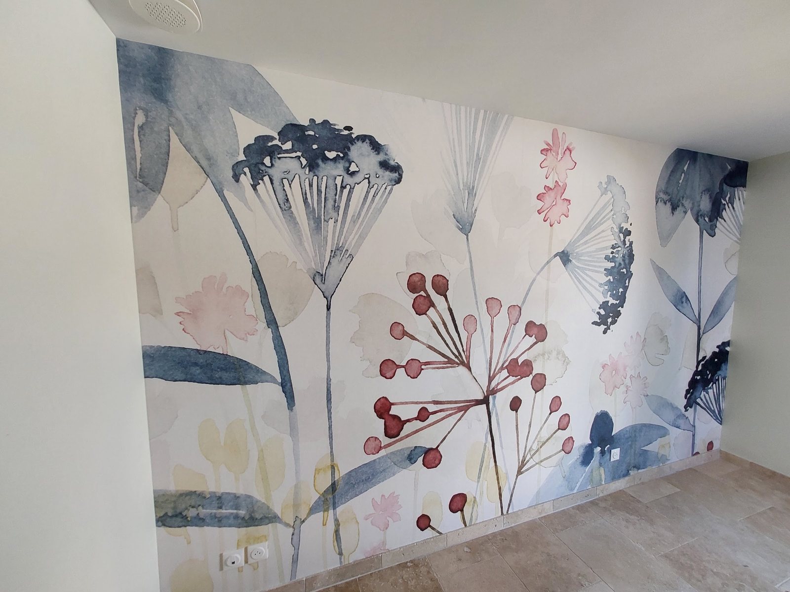 Papier peint panoramique à motif floral aquarelle posé par Viegas peinture, avec un raccord de lés suivi jusque dans l'angle du mur.