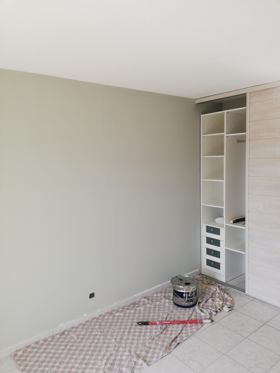 Chambre repeinte dans un vert de gris clair et mat, avec un placard intégré.