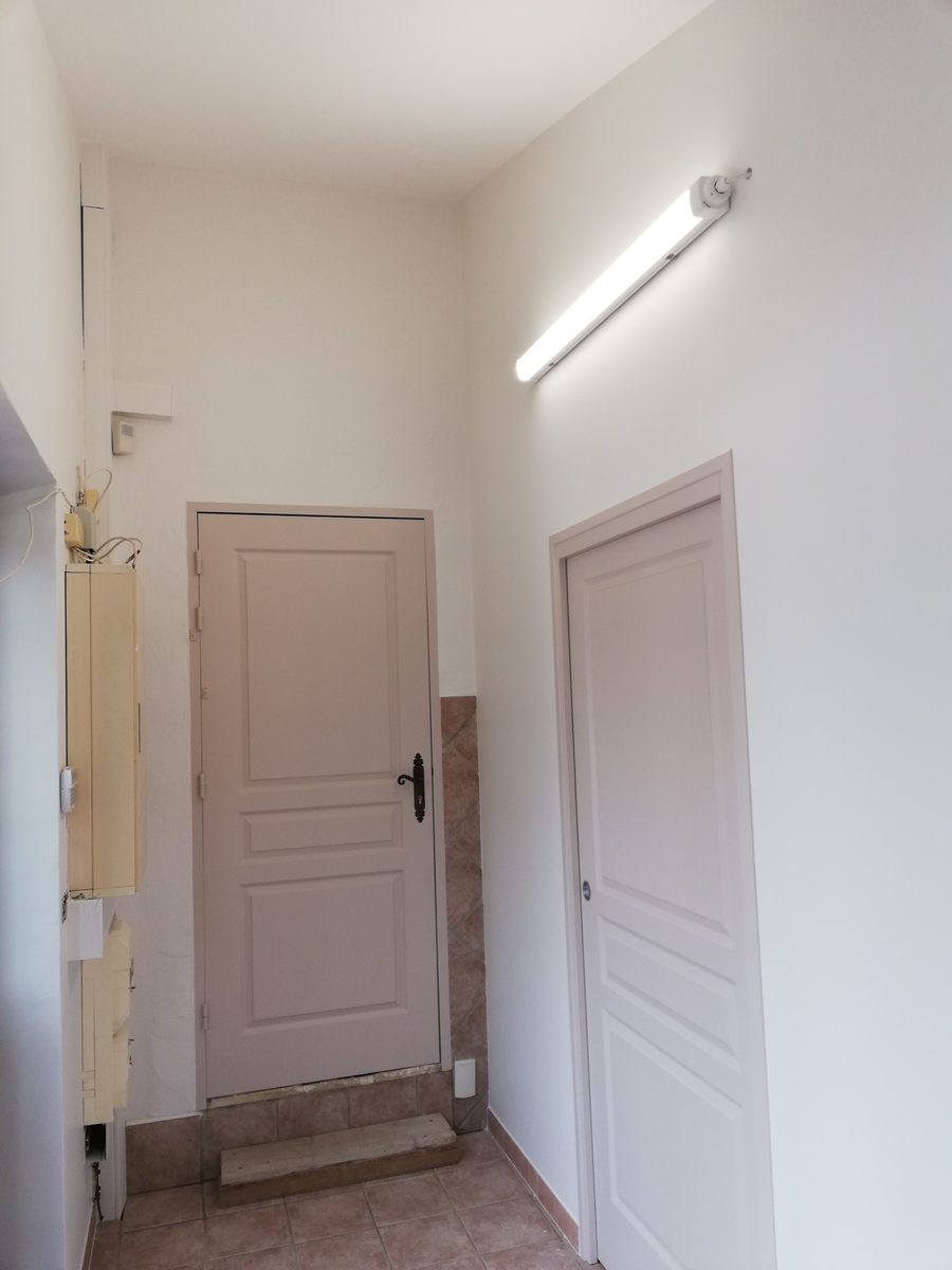 Entrée d'appartement repeinte, murs blancs et portes en rose poudré.