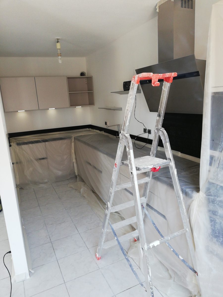 Cuisine dont les meubles et le plan de travail sont entièrement bâchés avant la mise en peinture.