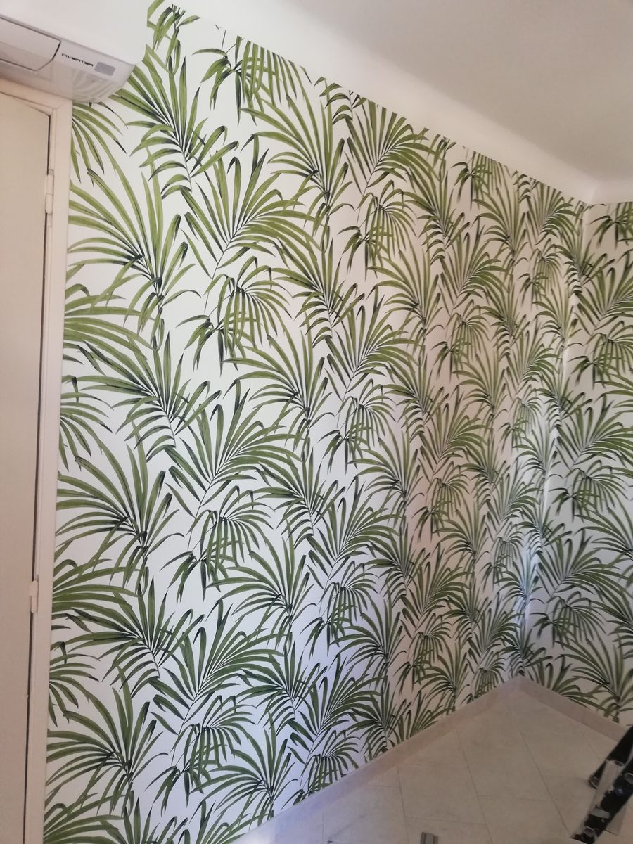 Mur d'angle tapissé d'un papier peint à motif de palmes vertes, raccord suivi dans l'angle.
