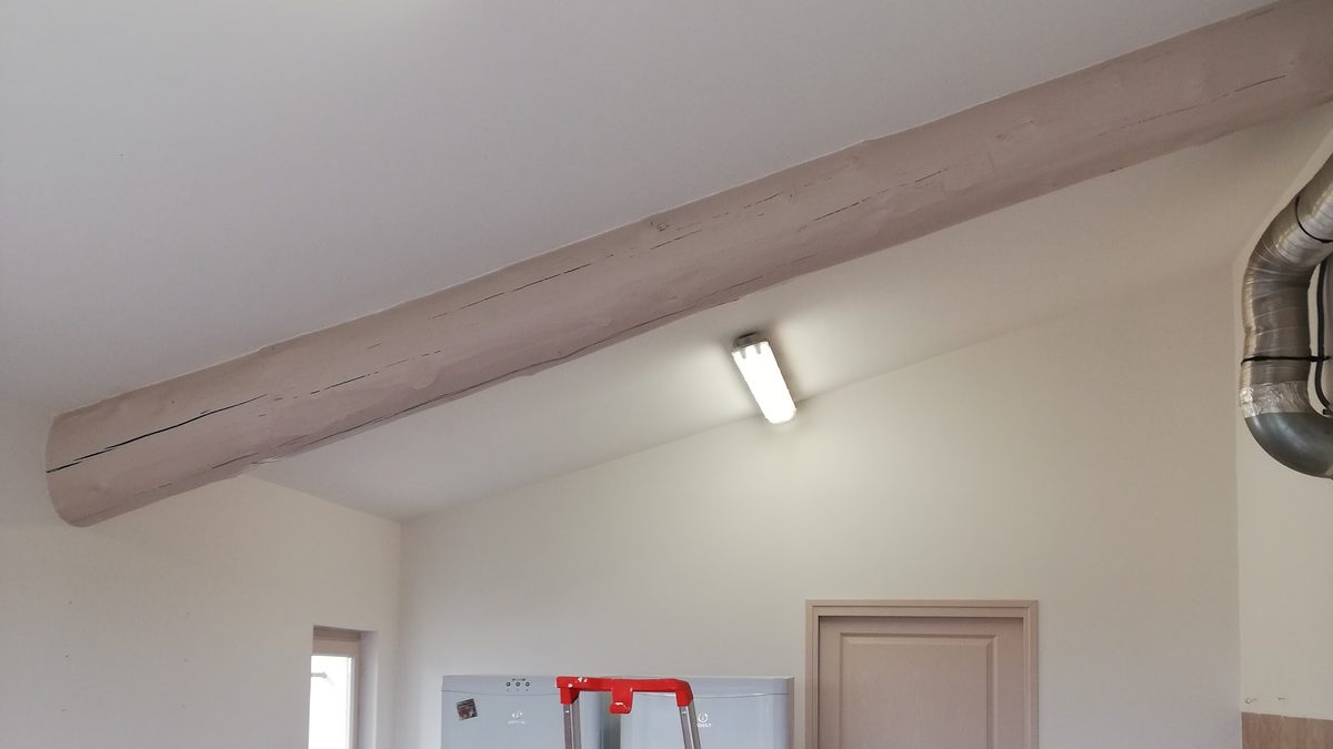 Plafond et poutre apparente repeints dans un ton taupe clair accordé aux murs.